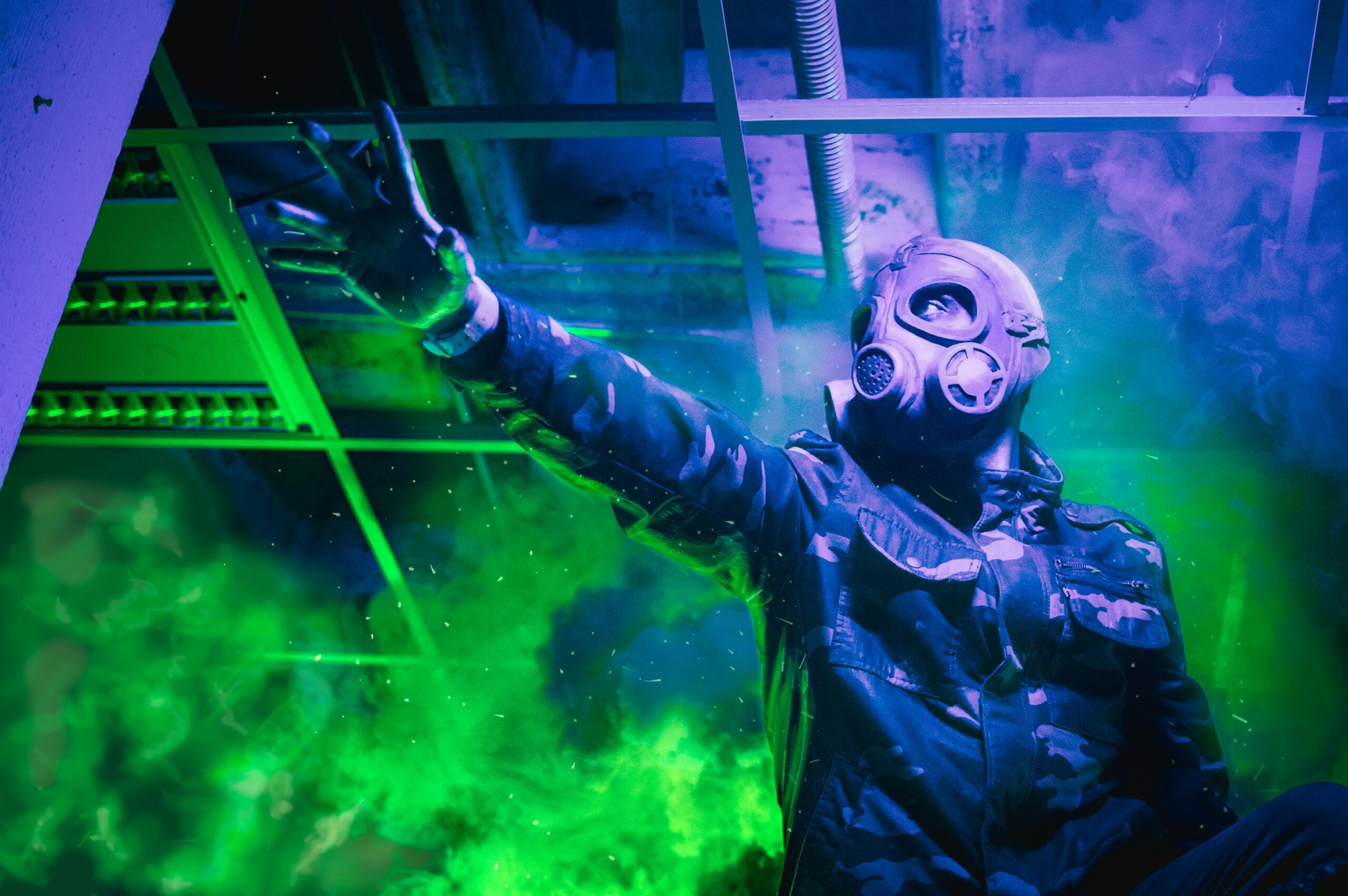 A person in a gas mask raises their hand amidst vibrant green smoke in a mysterious setting.